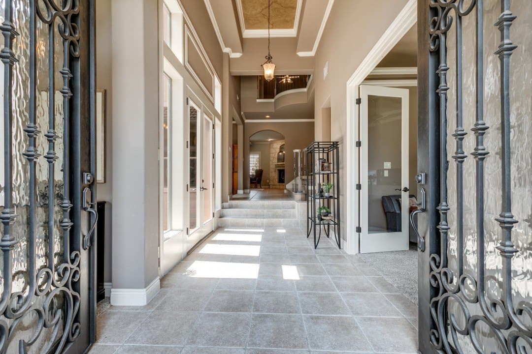 Entry hall with iron doors, tile floors, and a view through to a living room.